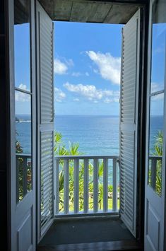 an open door leading to a balcony with the ocean in the background