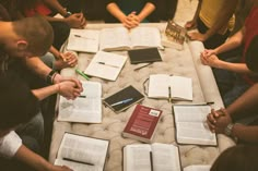 a group of people sitting around a table with open books