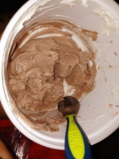 a white bowl filled with chocolate frosting next to a plastic spatula