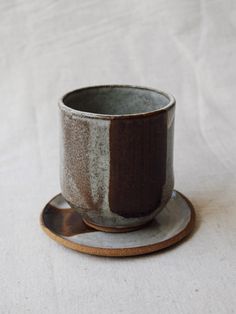 Handbuilt cup with a rounded bottom placed on a small plate being used as a saucer or coaster. Decorated in a white glaze with a red iron oxide stripe. Pottery Iron Oxide, Pottery Oxides, Iron Oxide Ceramics, Wax Resist Pottery, Oxide Ceramics, Handbuilding Techniques, Ceramic Handbuilding, Glaze Painting, Red Clay Pottery