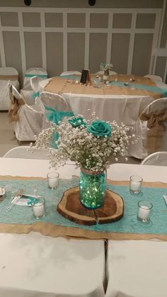 a vase with flowers on a table at a wedding reception in a room decorated with white and blue linens