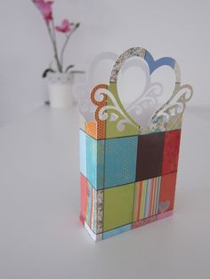 there is a small colorful box with hearts in it on the table next to a vase