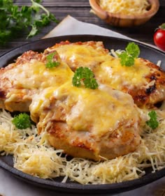 chicken parmesan with cheese and parsley in a skillet on a wooden table