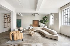 a living room filled with lots of furniture and large windows on the side of it