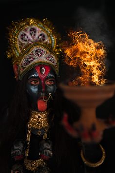 a woman with black face paint and red makeup holding a large vase in her hand