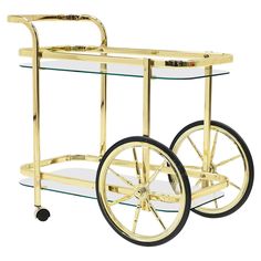 a gold bar cart with glass shelves and wheels on the bottom, is shown against a white background