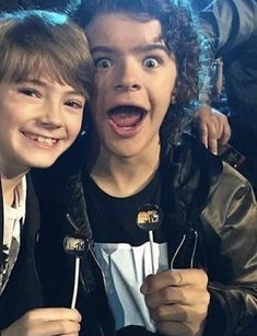 two young men are posing for a photo with lollipops in their hands