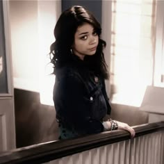 a woman standing on top of a balcony next to a window with sunlight coming through the windows