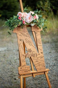 a wooden easel decorated with flowers and greenery