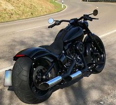 a black motorcycle parked on the side of a road next to a rural country road