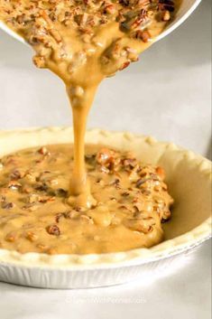 a pie crust being filled with caramel sauce and topped with pecanized nuts