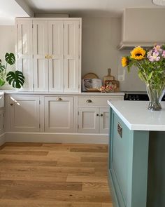 a kitchen with white cabinets and flowers in vases on the counter top next to an oven