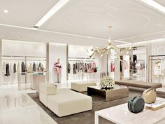 a white room filled with lots of furniture and clothing on display in front of a chandelier