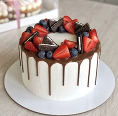 a cake with chocolate icing, strawberries and blueberries on top