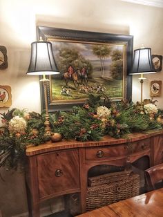 a painting on the wall above a table with flowers and greenery in front of it