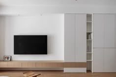 a flat screen tv sitting on top of a wooden shelf next to a white wall