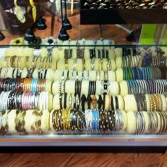 a display case filled with lots of different types of bracelets on top of a wooden table