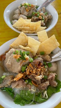 two white bowls filled with food on top of a wooden table