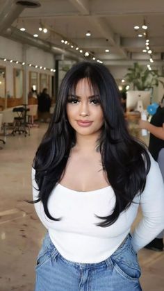 a woman with long black hair posing for the camera