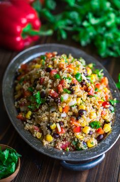 a plate filled with rice and vegetables on top of a wooden table next to peppers