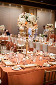 the centerpieces on this table are adorned with flowers and gold plates, along with silverware