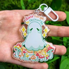 a hand holding a plastic keychain with a ghost on it's back