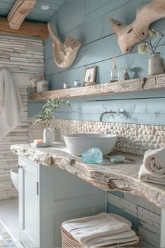 a bathroom with blue walls and stone counter tops, white cabinets and towels on the shelves