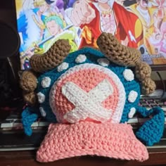 a crocheted hat is sitting on top of a laptop computer and it's cover has been made to look like a cartoon character