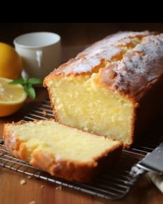 a loaf of lemon bread sitting on top of a cooling rack next to sliced lemons