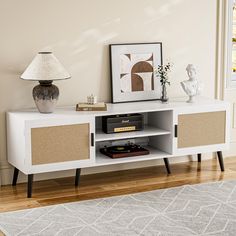 a white entertainment center with wicker doors and drawers in a living room next to a lamp