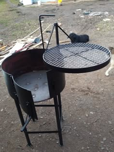 an outdoor grill with a dog laying on the ground next to it and another animal in the background