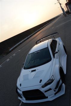 a white sports car is parked on the side of the road with its hood up