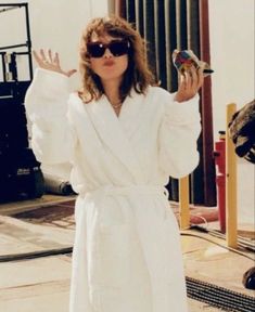 a woman in white robe holding up two birds