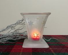 a lit candle sits on a plaid tablecloth