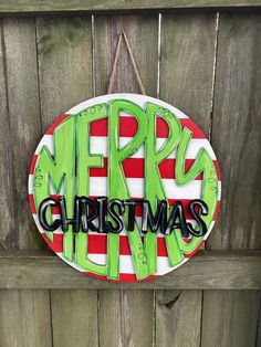 a merry christmas sign hanging on the side of a wooden fence with green and red stripes