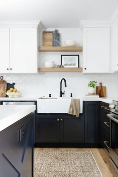 a kitchen with black cabinets and white counter tops is pictured in this image, there are shelves on the wall above the sink