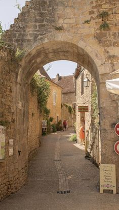 an arch in the stone wall leading to another building