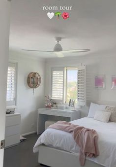 a bedroom with white furniture and pink accents on the walls, along with shuttered windows