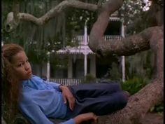 a woman sitting on top of a tree next to a house