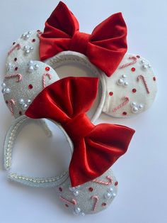 three minnie mouse ears with red bows and candy canes on them, all decorated in white