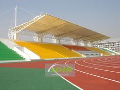 an empty stadium with red and yellow running tracks in front of the bleachers