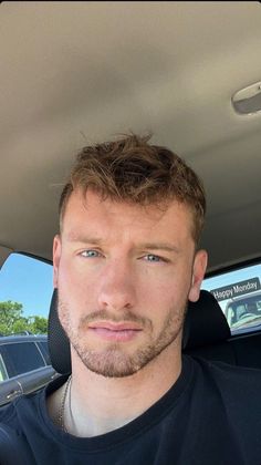 a man sitting in the back seat of a car looking at the camera with a serious look on his face