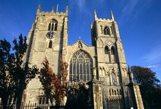 an old cathedral with two clocks on the front and side walls, surrounded by trees