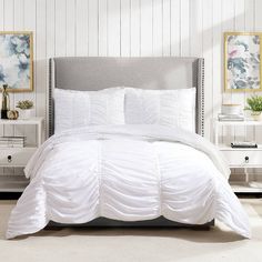 a bed with white comforter and pillows in a room next to two nightstands