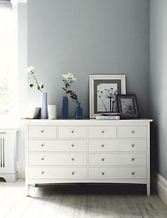 a white dresser with flowers and pictures on top