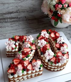 a number shaped cake sitting on top of a cutting board next to a vase with flowers