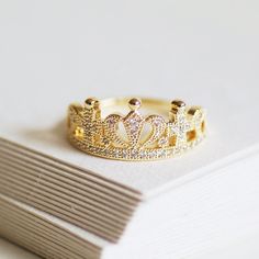 Feel like a Queen with our Dainty Crown Ring. Intricately designed, this detailed ring - made with gold-plated brass and cubic zirconia - is sure to add a touch of sparkle. The ring is gift-wrapped in white tissue and comes in an exclusive Carriage Trade gift box free of charge. Available in three sizes, L/6 (small), N/7 (medium) and P/8 (large). Please see the conversion chart to find your ring size. Made from 18ct gold-plated brass and cubic zirconia. Gold Crown Ring, Jewellery Dainty, Crown Ring Princess, Minimalist Jewellery, Princess Ring, Crown Ring, Detailed Ring, Ring Minimalist, Gold Crown