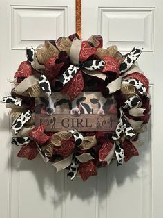 a cow print wreath hanging on a door with the word my girl written in it