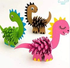 three paper dinosaurs with pine cones on their heads and one dinosaur holding a pine cone