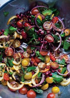 a salad with tomatoes, onions, spinach and other veggies in it